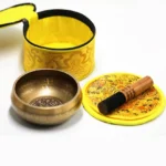 Complete handcrafted brass singing bowl meditation set with wooden mallet, embroidered cushion, and storage bag displayed in flat lay arrangement