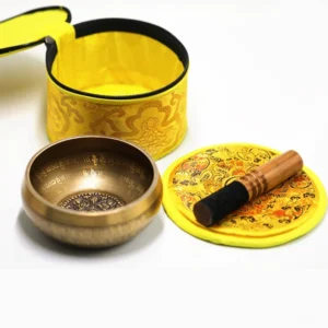 Complete handcrafted brass singing bowl meditation set with wooden mallet, embroidered cushion, and storage bag displayed in flat lay arrangement