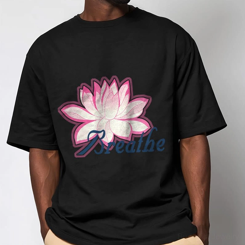 Men wearing breathe lotus flower black t-shirt with large pink lotus graphic and dark blue text, indoor plain backdrop