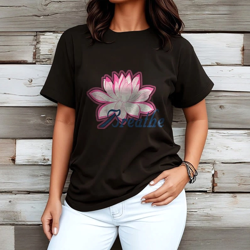 Woman wearing breathe lotus flower black t-shirt with pink lotus and dark blue text print on wooden wall background