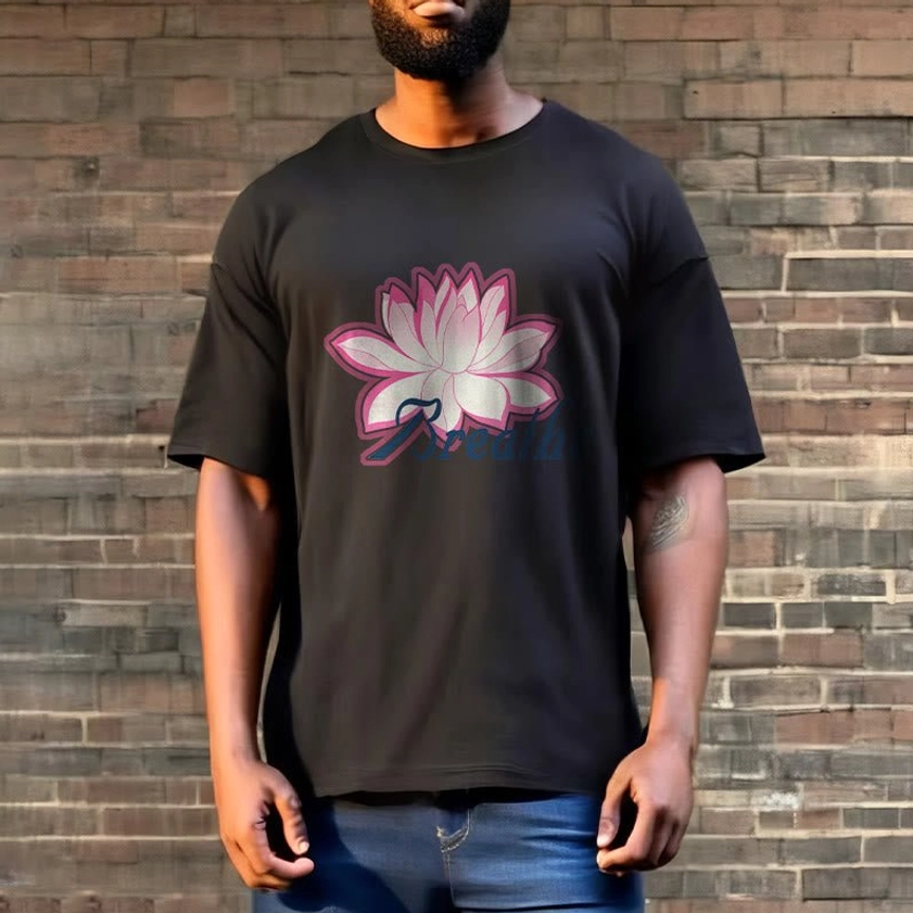 Man wearing breathe lotus flower dark gray t-shirt with pink lotus graphic on brick wall background