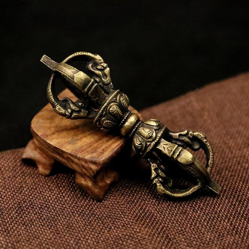 Bronze five-prong vajra dorje with intricate hand-carved relief details, showing antique metal finish from artisan craftsmanship