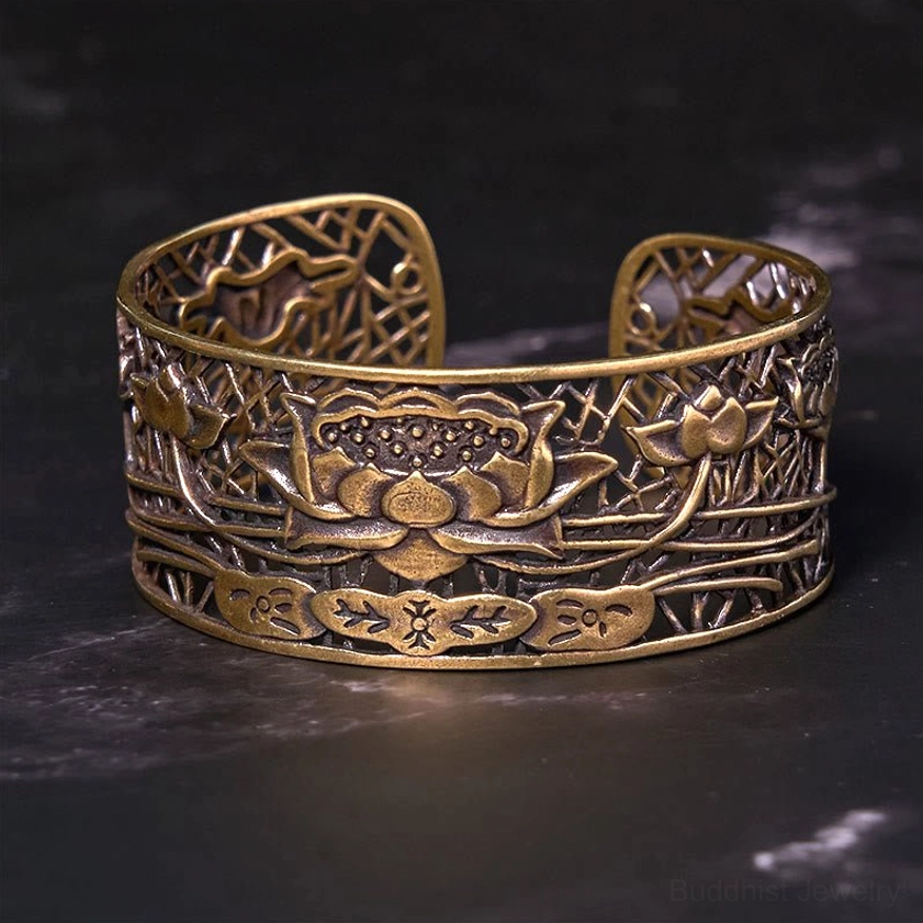 Front-facing close-up of bronze lotus carved cuff bracelet with intricate hollowed lotus and foliage relief motifs on dark backdrop