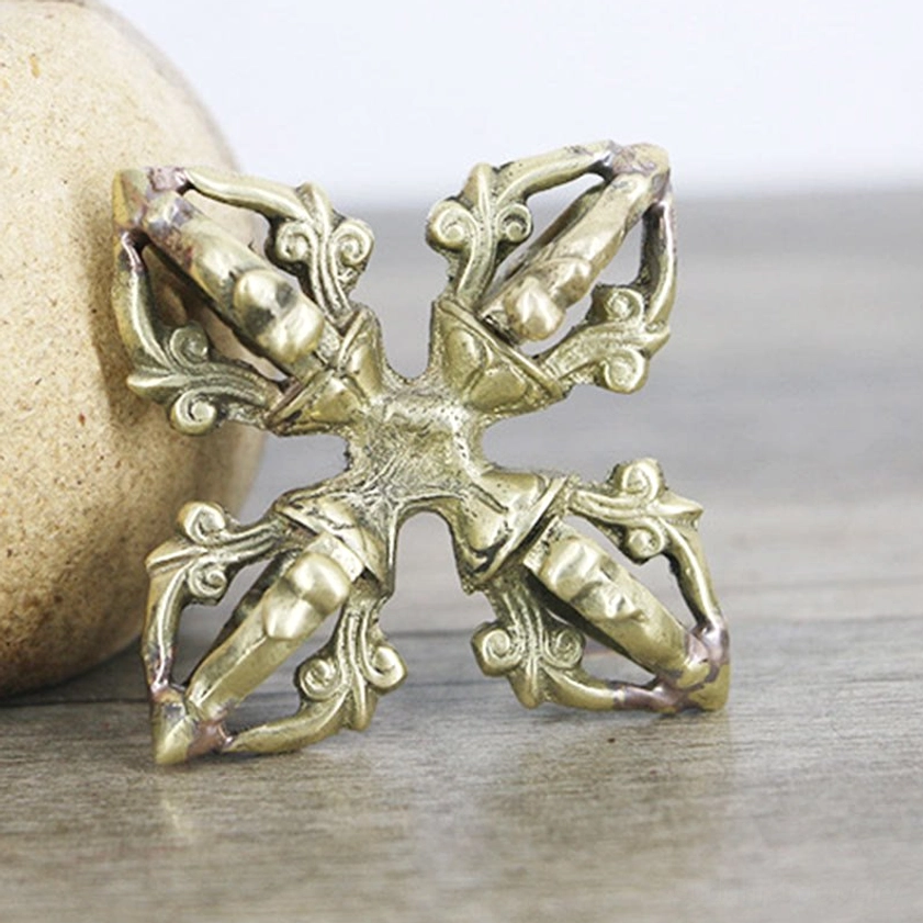 Antique bronze finish vajra three-quarter side view beside beige stone showing detailed decorative carvings