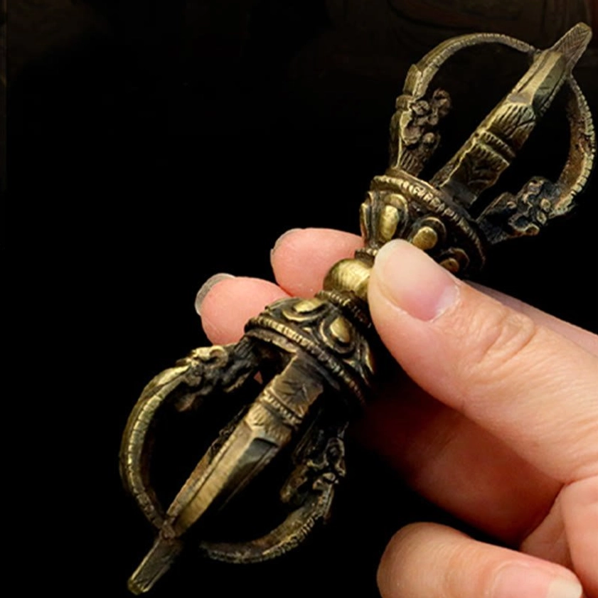 Handmade bronze five-prong vajra dorje held in human hands, showing clear carved texture and aged metal surface