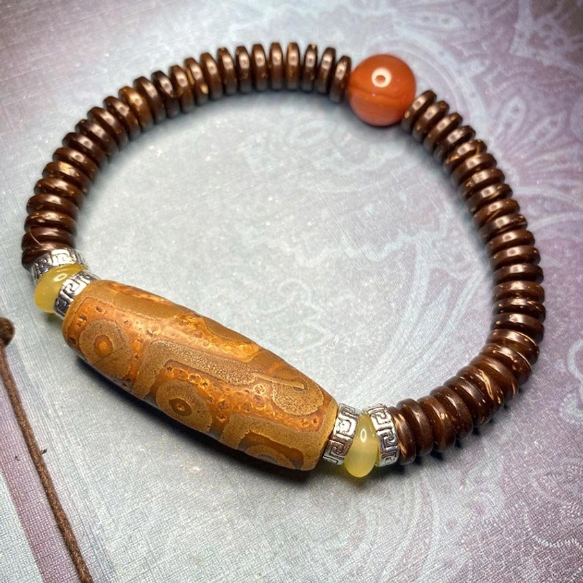 brown nine-eye dzi bead bracelet with aged matte texture, coconut shell beads, and amber accents for wealth and protection