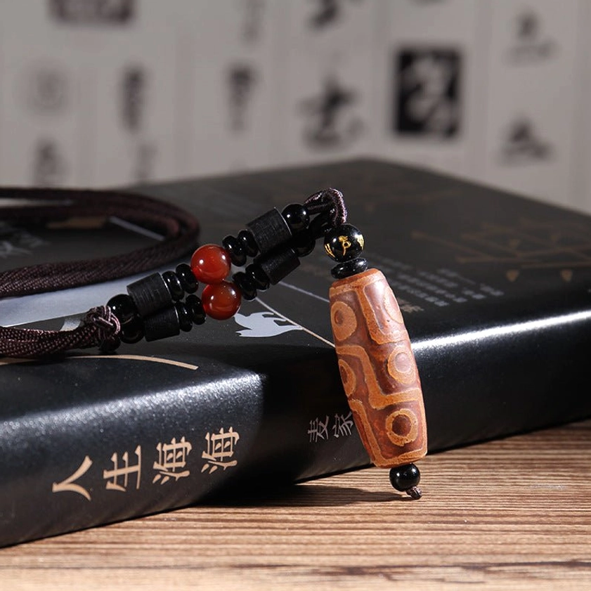 Brown patterned nine-eye dzi bead necklace with natural cord and red agate bead accents