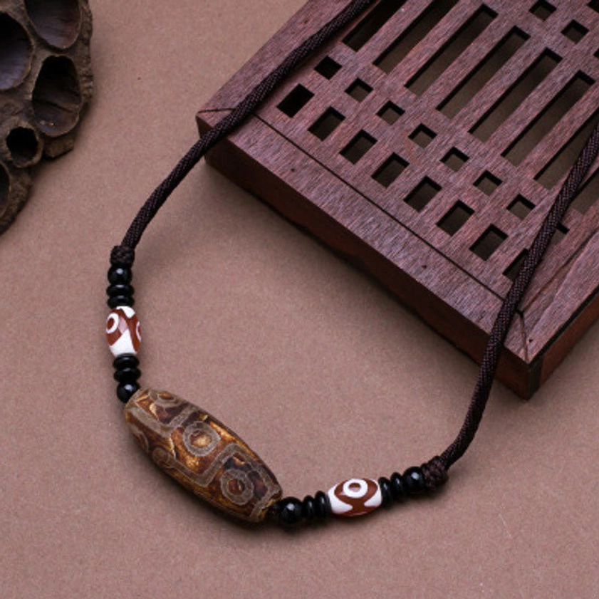 Brown nine-eye vintage dzi bead necklace with matte finish agate stone and black spacer beads, overhead flat lay photography