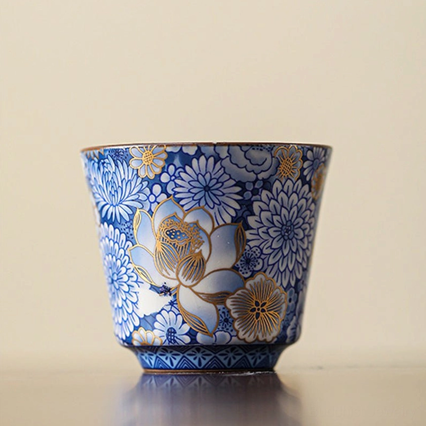 Tall bucket-shaped gilded blue and white porcelain teacup with full lotus and floral patterns