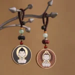 Buddha and Avalokitesvara wooden keychains with beaded lanyards displayed on branch stand - Buddhist spiritual charm