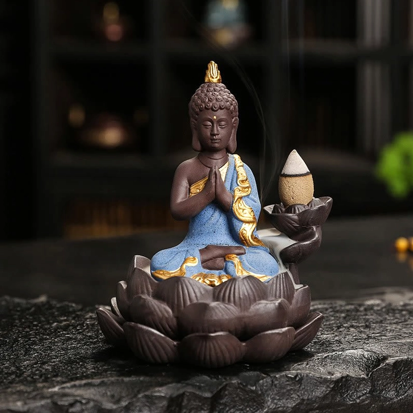 Blue Buddha ceramic incense burner with meditation mudra pose on dark tabletop for mindfulness practice