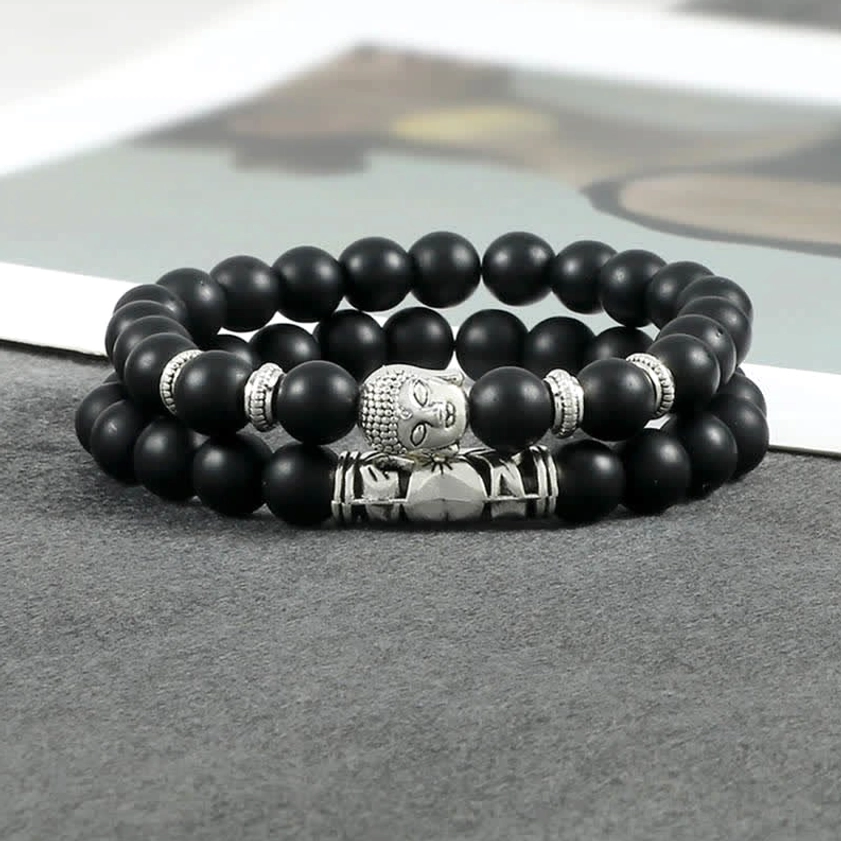 Close-up side view of black stone Buddhist healing bracelet showing bead texture and silver Buddha charm detail