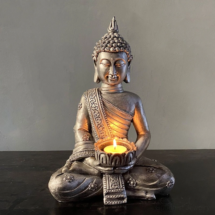 Dark aged silver-bronze Buddha candlestick holder front view with lit tealight, displaying intricate carved patterns and mindfulness aesthetic