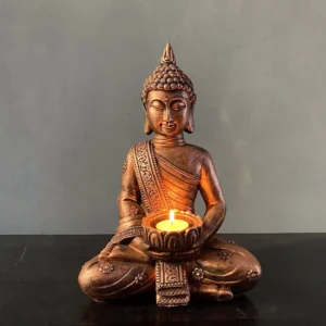 Antique bronze Buddha candlestick holder with lit tealight candle, front view showing intricate carved robe details and serene face