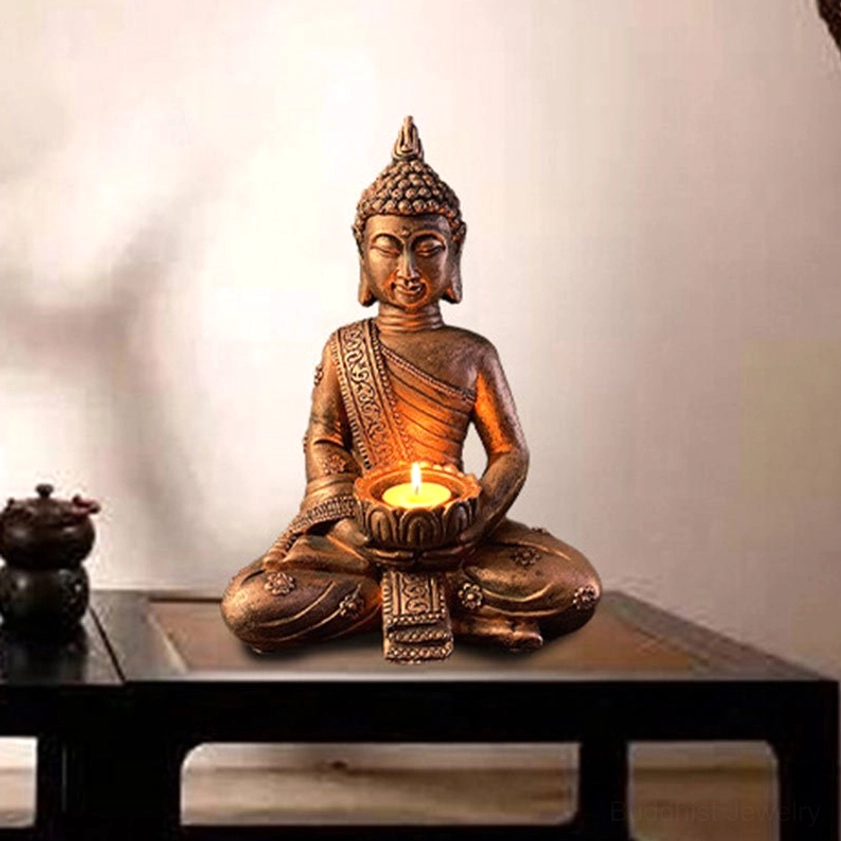 Handcrafted Buddha candlestick holder three-quarter angle view on wooden table with home décor, showing carved robe texture and lit tealight