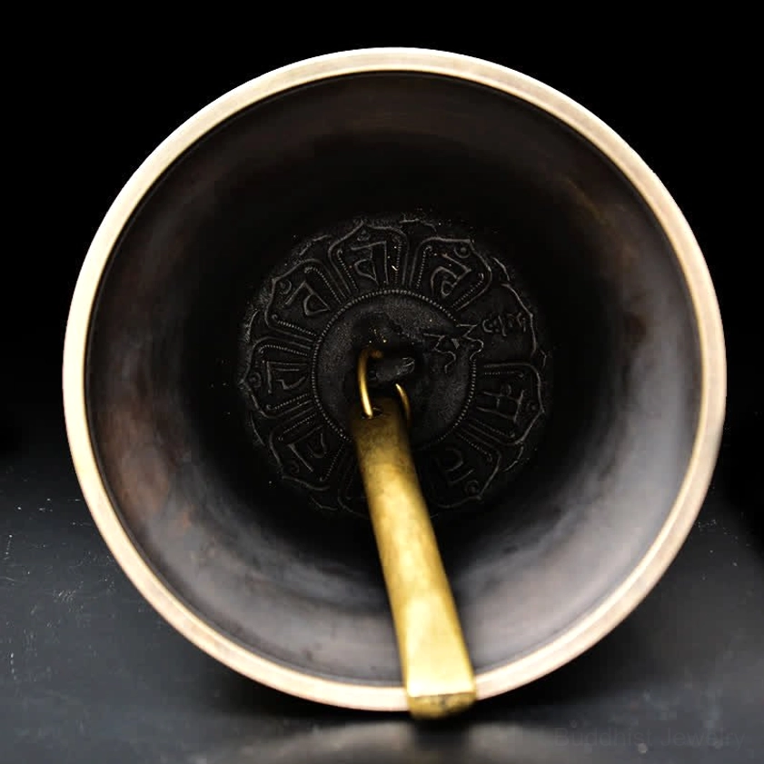 Interior top-down view of copper chime bell showing inscribed Buddhist mantras inside and brass clapper mechanism
