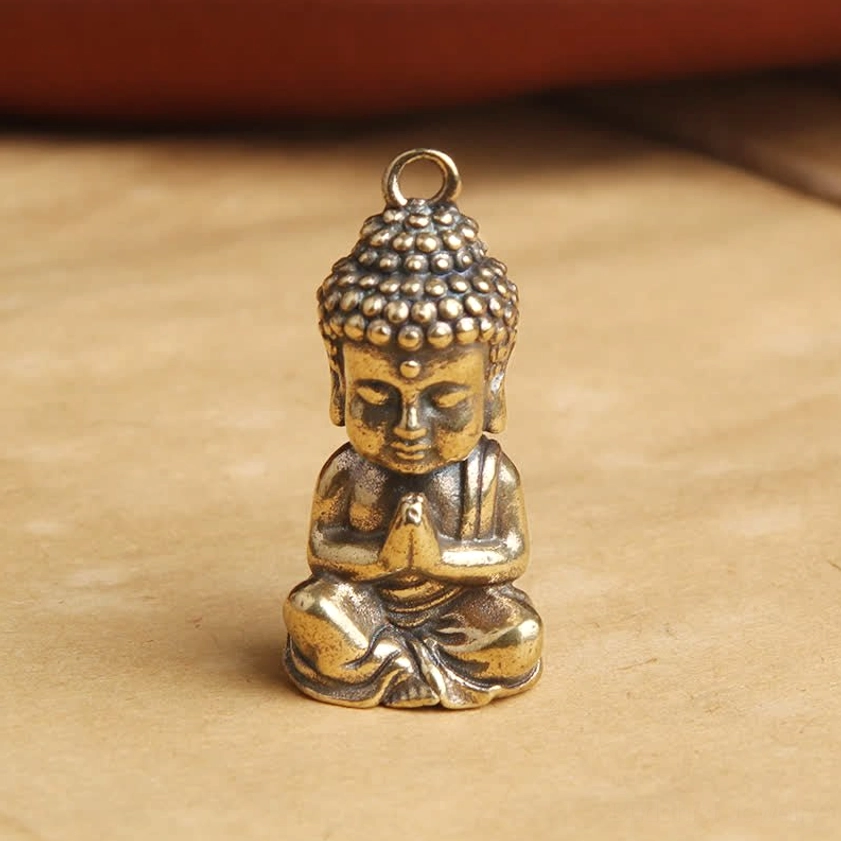 Close-up frontal view of meditating Buddha copper pendant showing detailed facial features and aged bronze patina