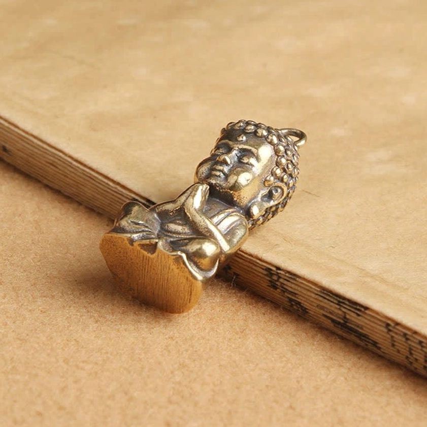 Tilted overhead view of meditating Buddha copper pendant highlighting aged bronze finish and handcrafted details