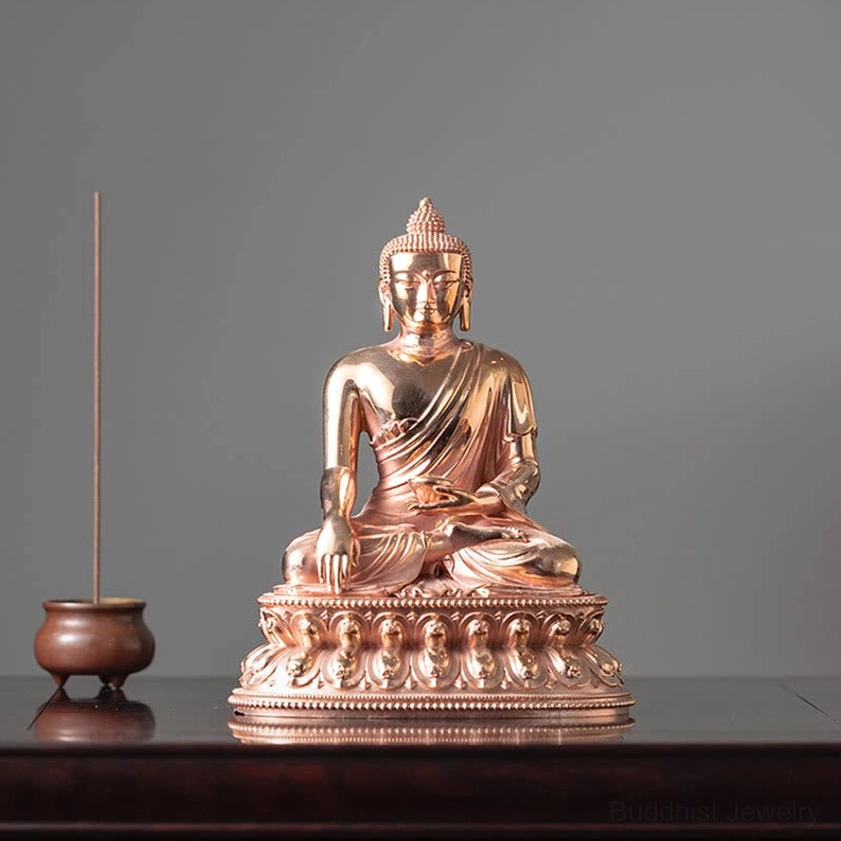 Buddha figurine displayed on wooden table with incense burner and ornate lotus throne details