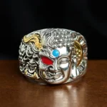 Half demon half Buddha lotus copper adjustable ring with turquoise and red agate inlay, front overhead view showing dual-face carving and intricate relief design