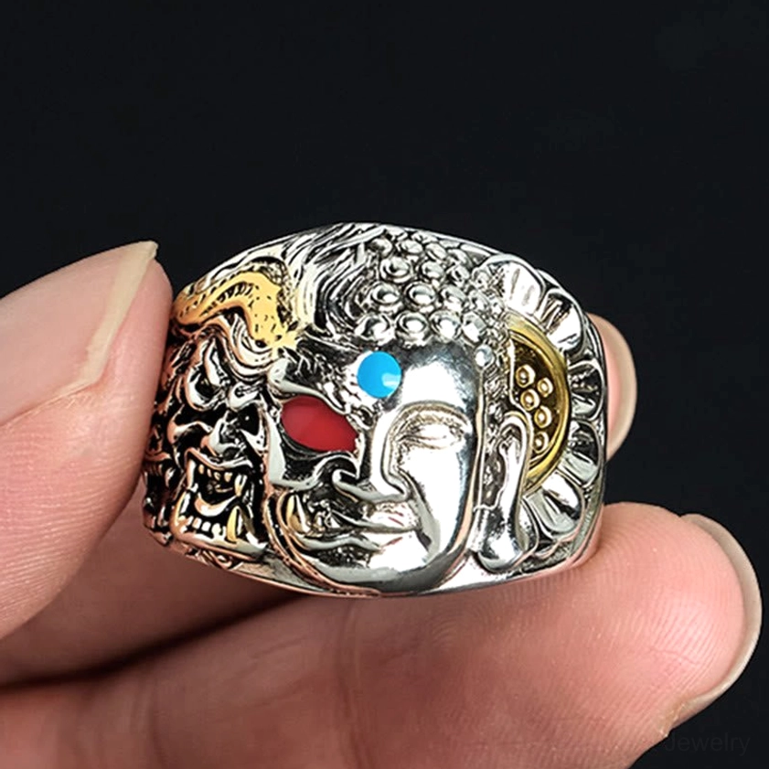 Buddhist adjustable ring on fingertip, close-up side view displaying polished copper finish and detailed facial carvings of Buddha and demon faces