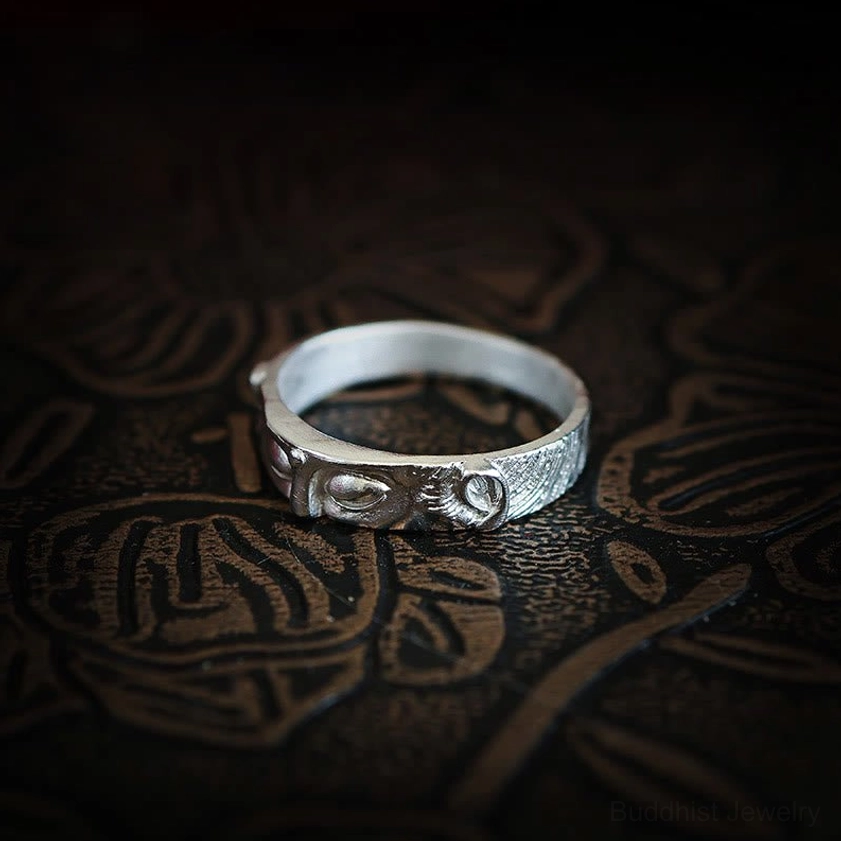 Angled top view of handcrafted Buddha eyes protection ring with complete carved eye design and striped texture details