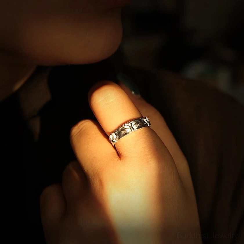 Buddha eyes silver ring worn on hand in indoor warm lighting, showing real-life wearing on index finger