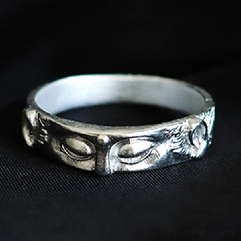 Close-up side view of handcrafted Buddha eyes ring showing detailed embossed design and decorative engravings on pure black background