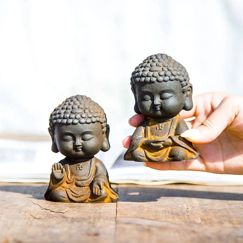 Hand-held size reference of small Buddha statue figurine against wooden background demonstrating compact portable dimensions