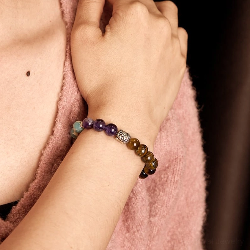 Side view of multicolor crystal Buddha bracelet worn on wrist with skin and fabric background
