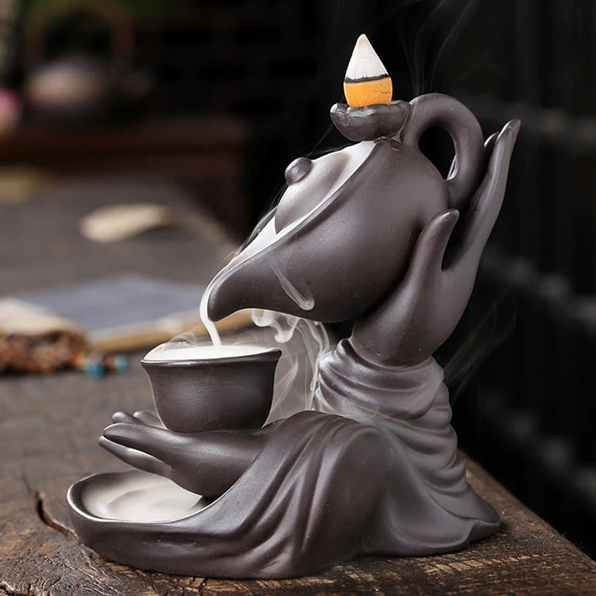 Right perspective of Buddha hand ceramic teapot burner with smoke cascading down into collection cup