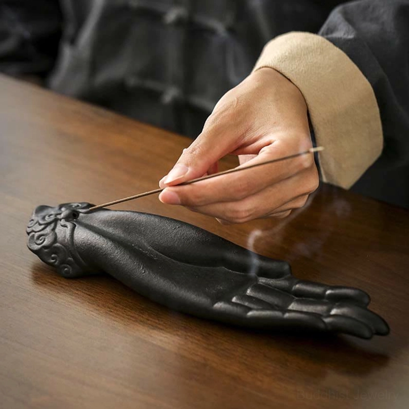 Buddha hand incense burner three-quarter side view with smoking incense stick and cloud carved wrist detail