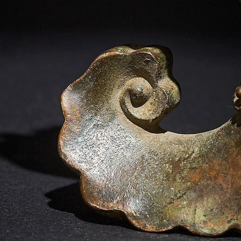 Close-up detail of curved ruyi-style base on brass Buddha's hand lotus statue - aged bronze texture and patina