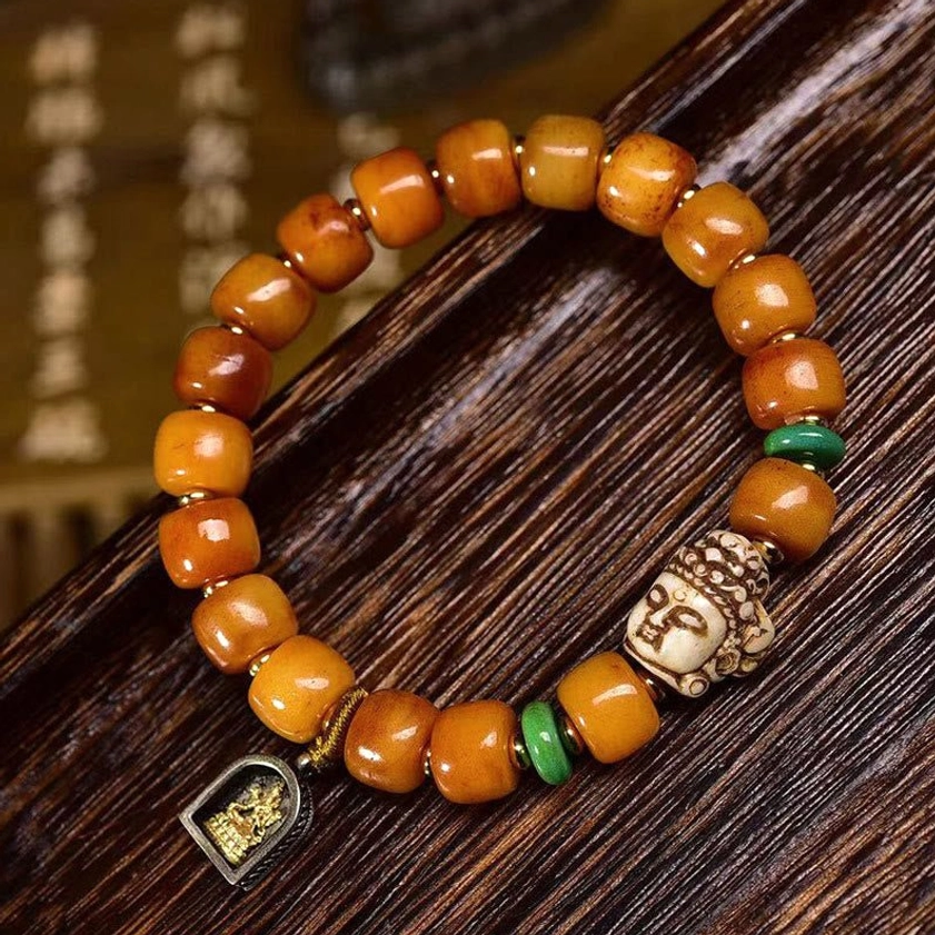 Close-up detailed view of Buddhist camel bone prayer bracelet showing intricate carved Buddha head bead, warm brown bone beads, green accent spacers, and artisan craftsmanship
