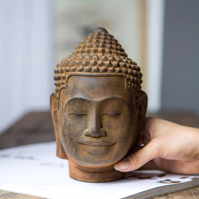 Detailed view of meditating Buddha head statue showing weathered rust-cast resin finish and traditional spiritual craftsmanship
