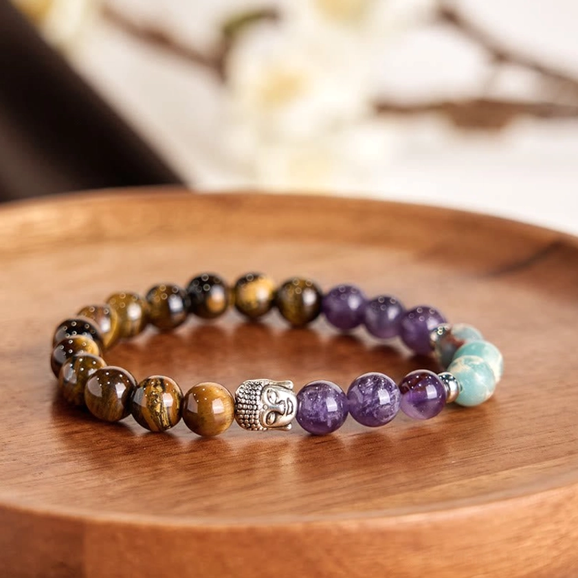 Close-up top view of multicolor crystal Buddha head bracelet with protective gemstones on wooden surface