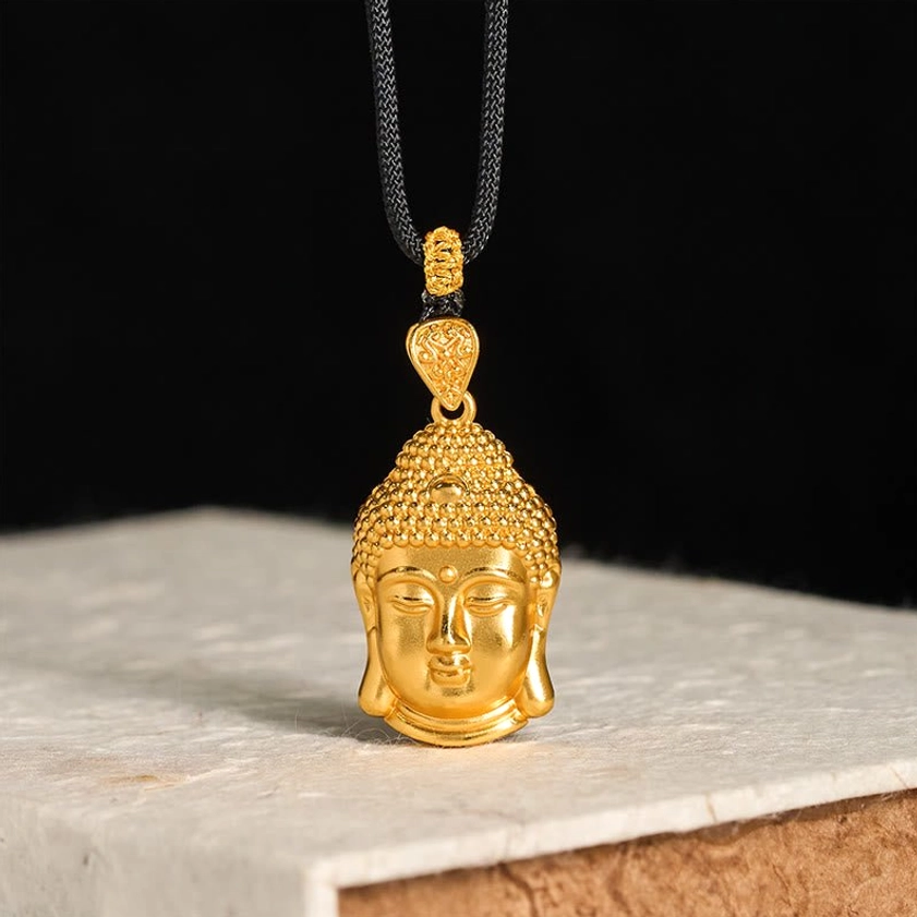 Ornate 24k gold Buddha pendant with detailed facial features and decorative bail