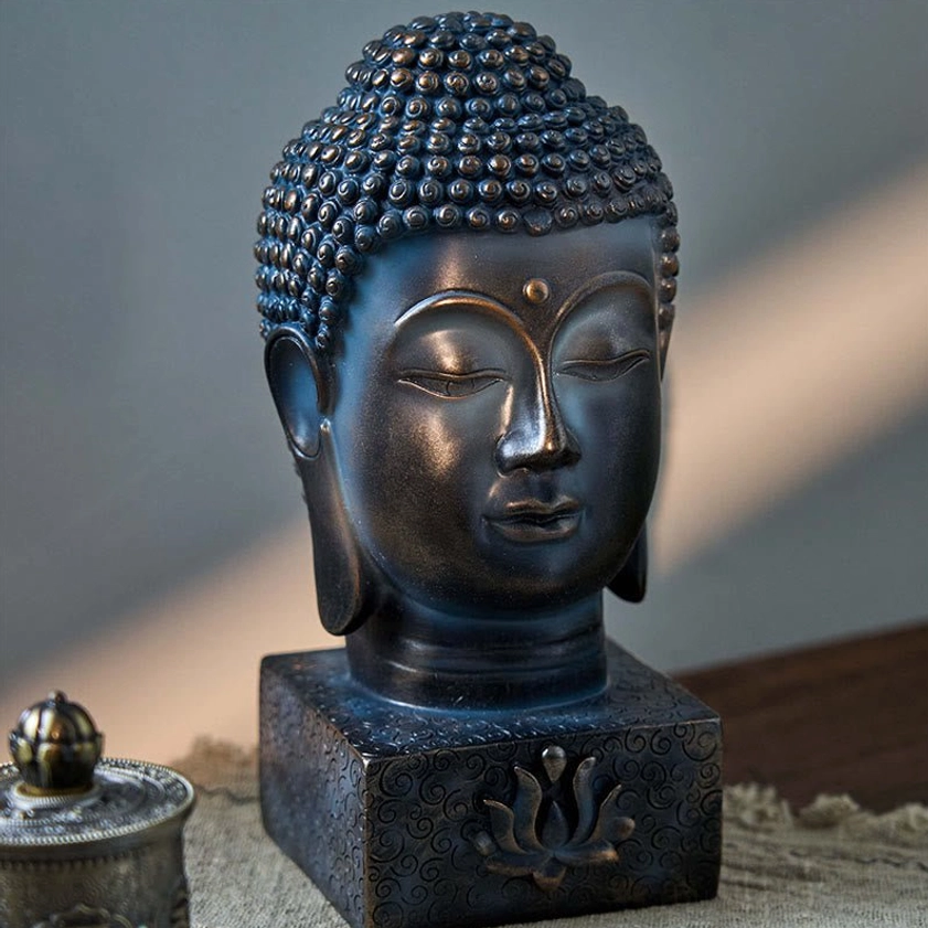 Buddhist Buddha head ornament three-quarter angle, dark blue-bronze hue with lotus base carving, tabletop spiritual décor