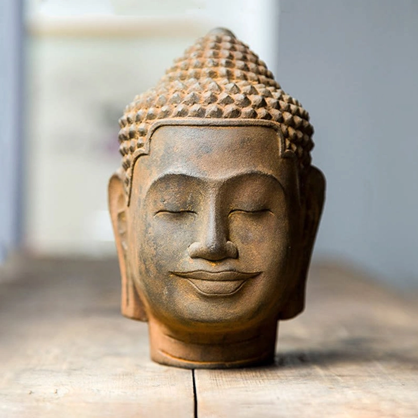 Three-quarter view of serene Buddha head statue emphasizing closed eyes, peaceful expression, and rust-brown weathered surface