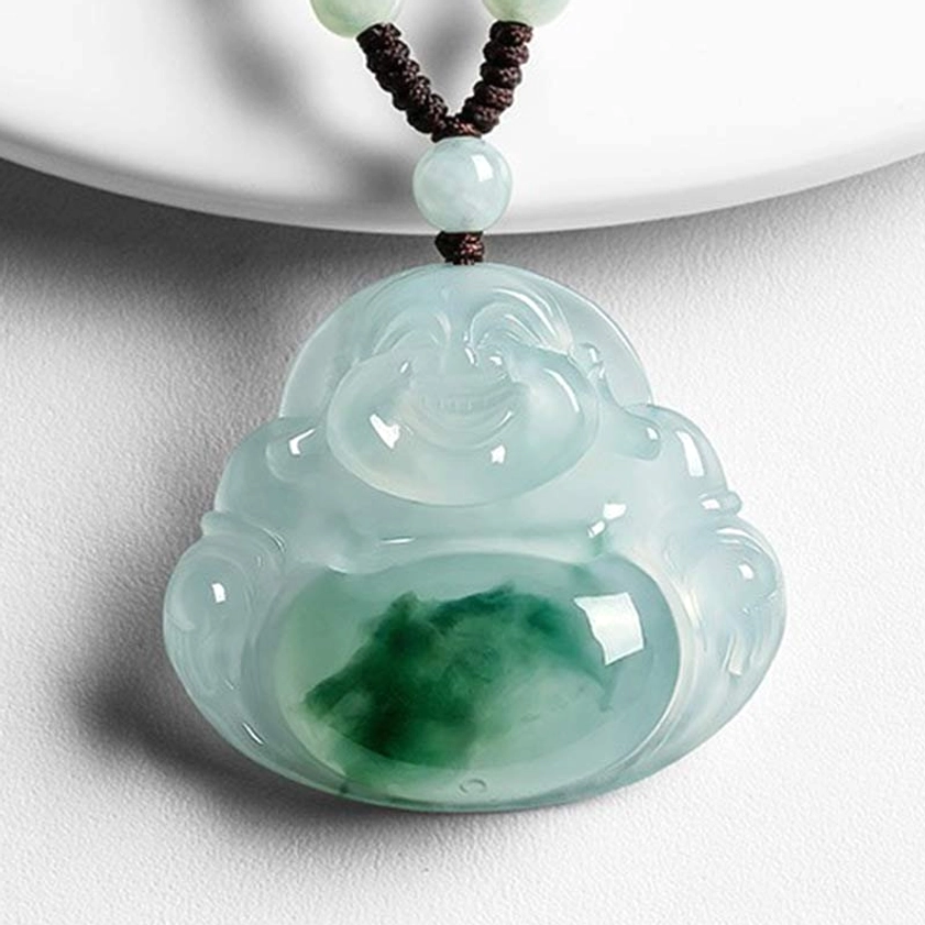 Handcrafted cyan jade Laughing Buddha pendant with carved smiling expression, green jade belly patch, brown rope cord with jade bead on white background