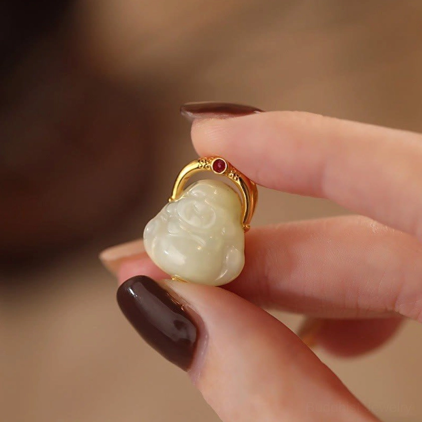 Close-up detail of hand-carved Laughing Buddha jade pendant with sterling silver frame and red gem accent