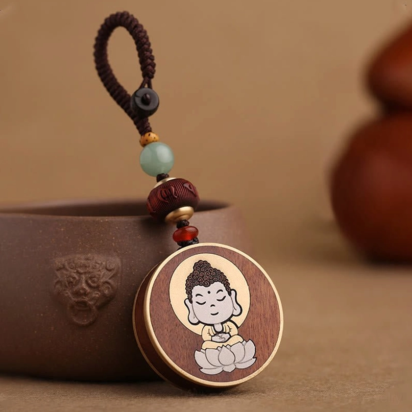 Buddhist keychain detail shot showing carved Buddha symbol and wood grain texture