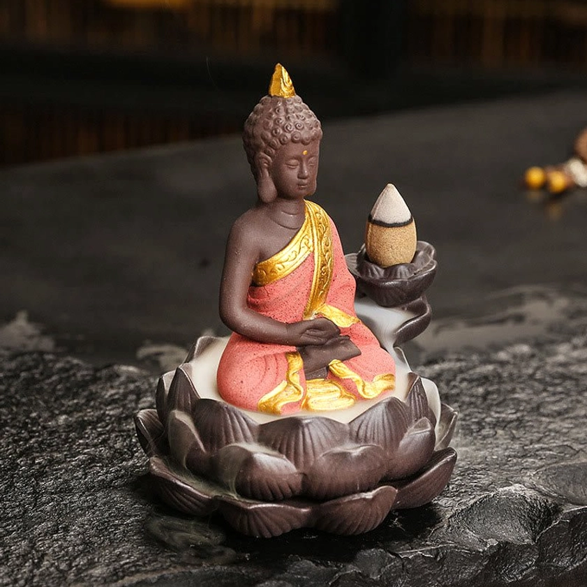 Ceramic Buddha incense burner with meditation mudra pose in red and gold finish, oblique angle tabletop display