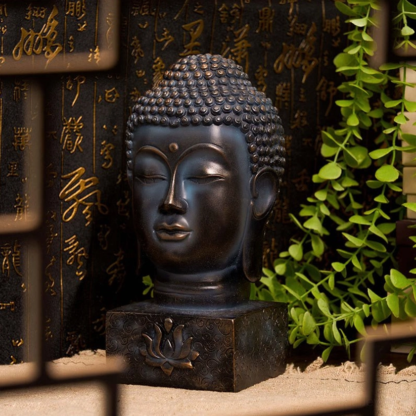 Handcrafted Buddha statue head closeup with serene expression, lotus engraved base, displayed with calligraphy backdrop