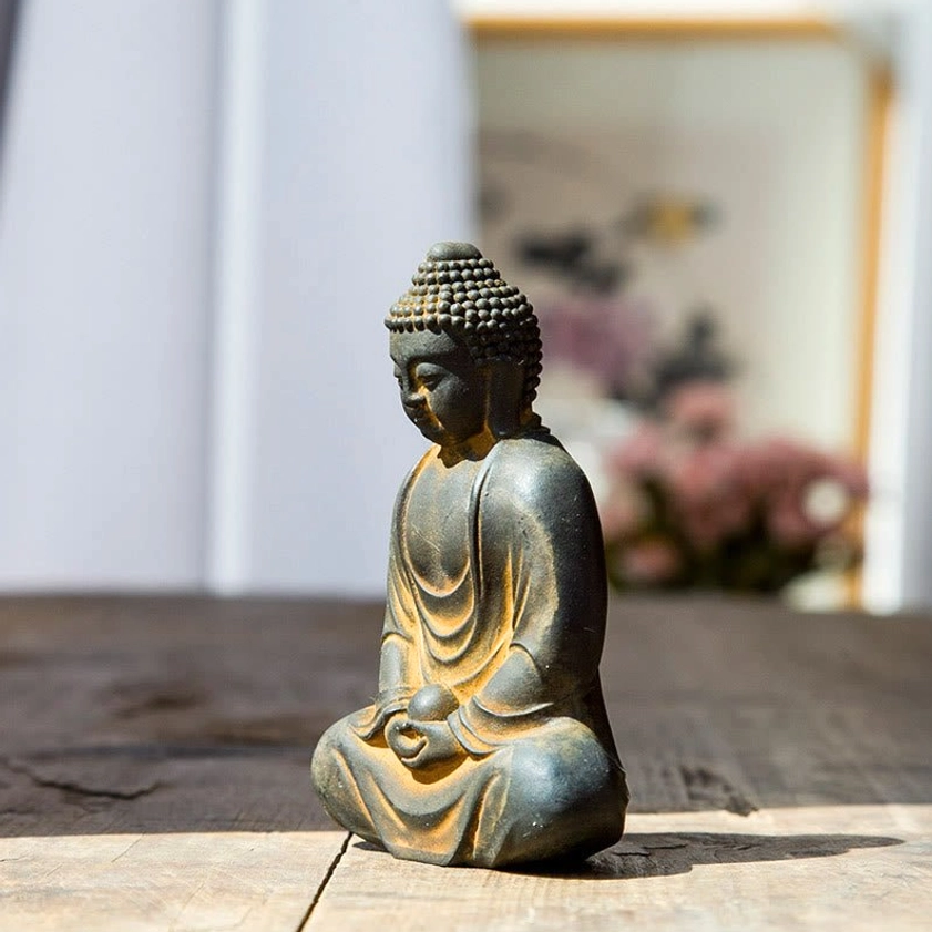 Meditating Buddha statue side profile view, cross-legged seated pose, dark grey with yellow decorative accents
