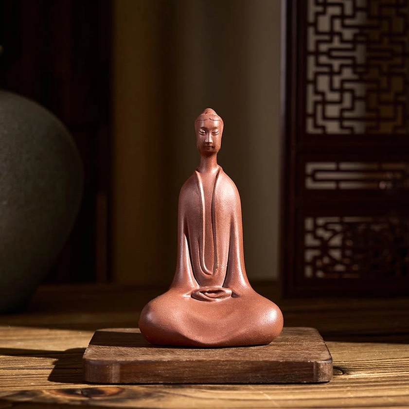 Buddha clay figurine three-quarter angle, displayed on wooden table with traditional backdrop