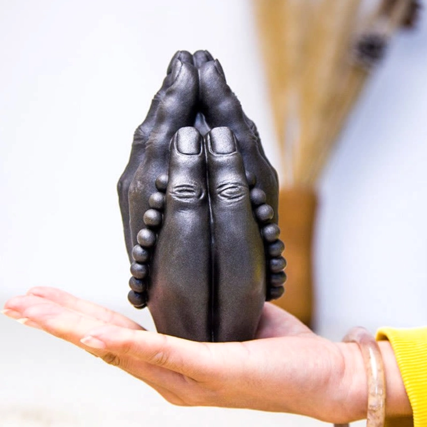 Buddha hand Namaste decoration with prayer beads and carved details on wooden table surface for home sanctuary
