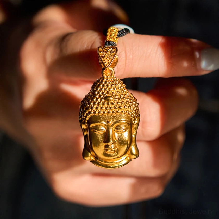 Hand holding gold plated Buddha pendant showing shiny finish and top bail