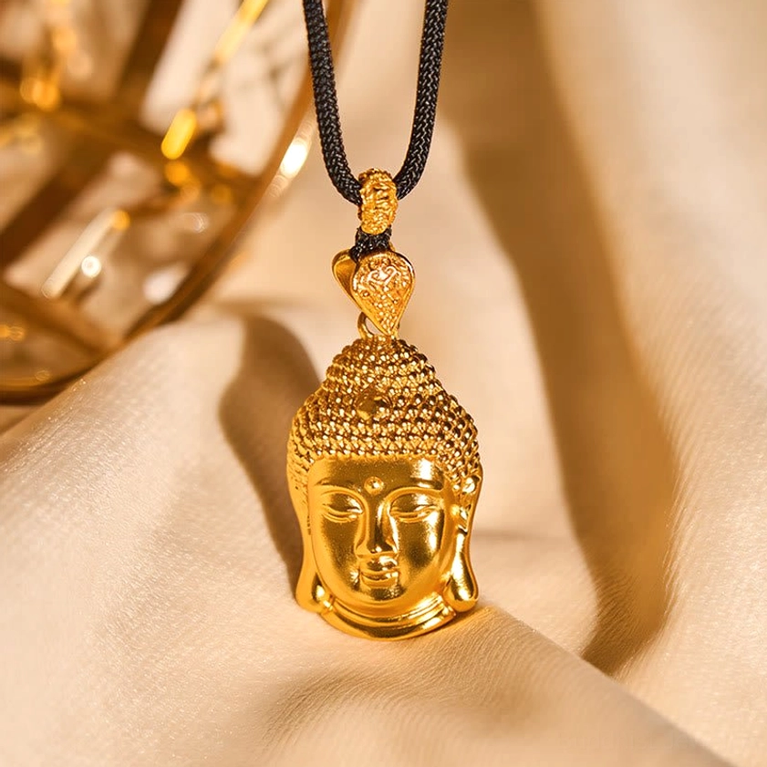 Buddha head pendant with braided black cord on fabric surface display
