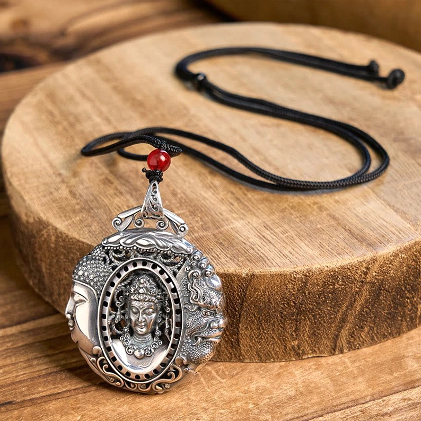 Copper Buddha pendant with red bead accent on black braided rope chain, front close-up on wooden display